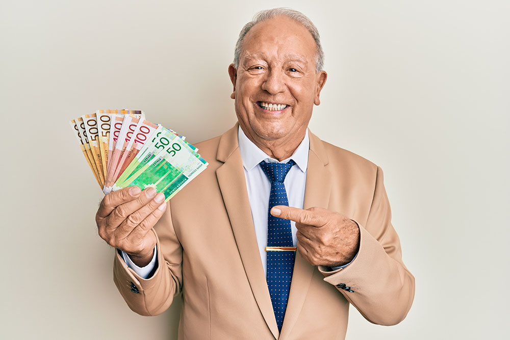 senior,caucasian,man,holding,norwegian,krone,banknotes,smiling,happy,pointing