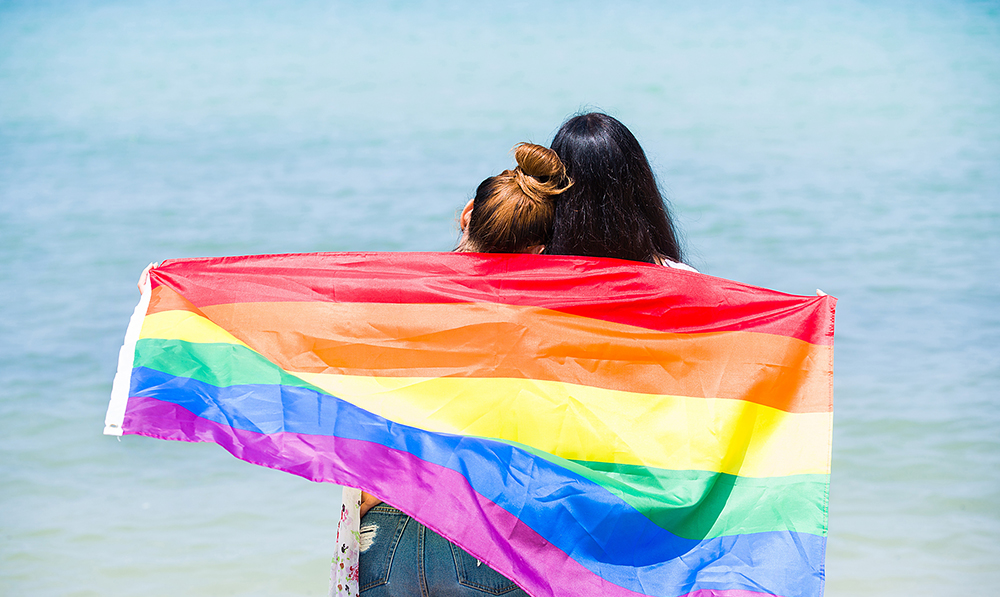 lgbtqi,couple,on,the,beach,with,rainbow,flag,beautiful,female
