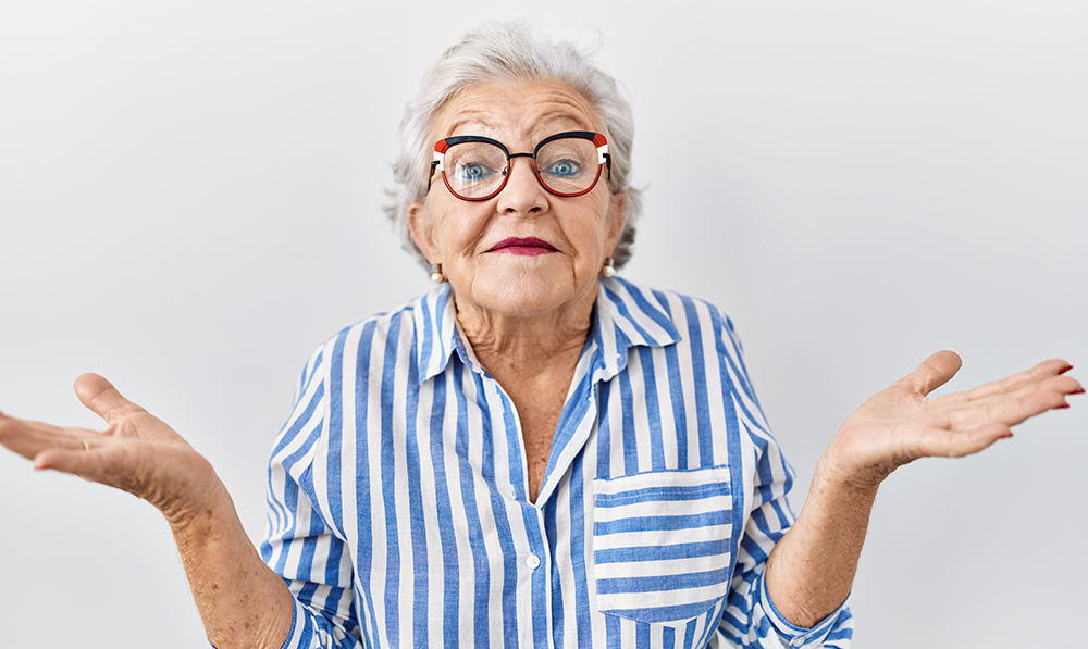 senior,woman,with,grey,hair,standing,over,white,background,clueless