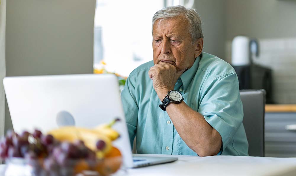 elderly,man,using,laptop,at,kitchen,table