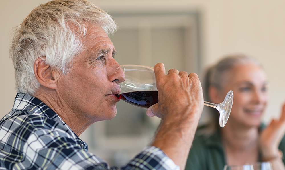 happy,senior,man,drinking,a,glass,of,red,wine,during