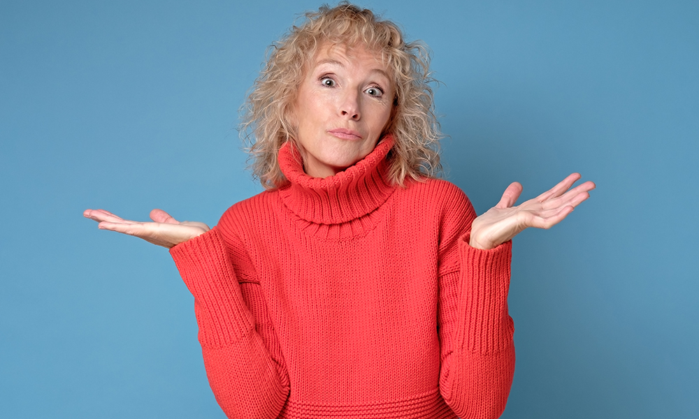 quizzically,attractive,senior,female,in,red,sweater,on,blue,background.