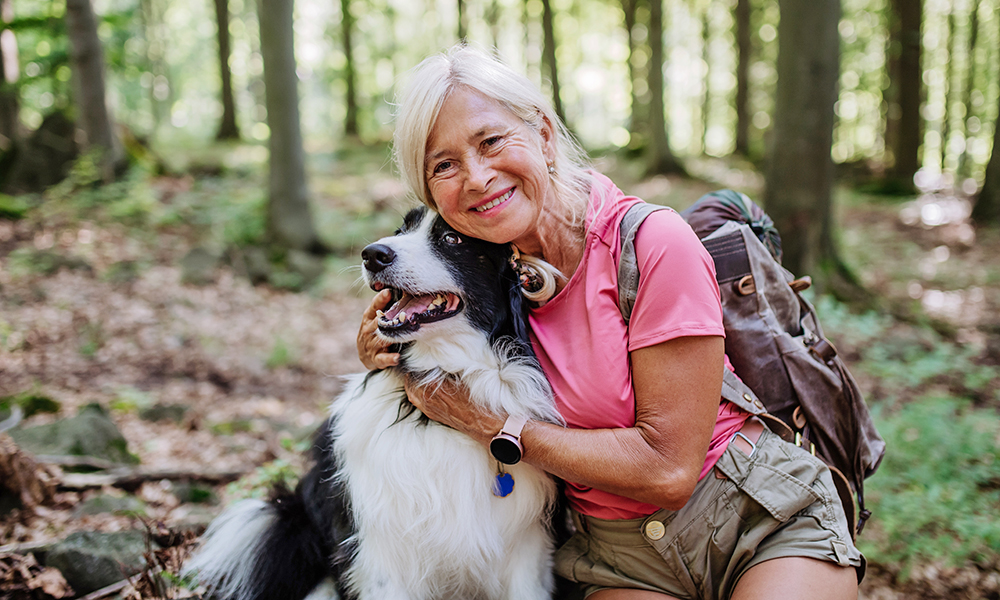 senior,woman,resting,and,stroking,her,dog,during,walking,in