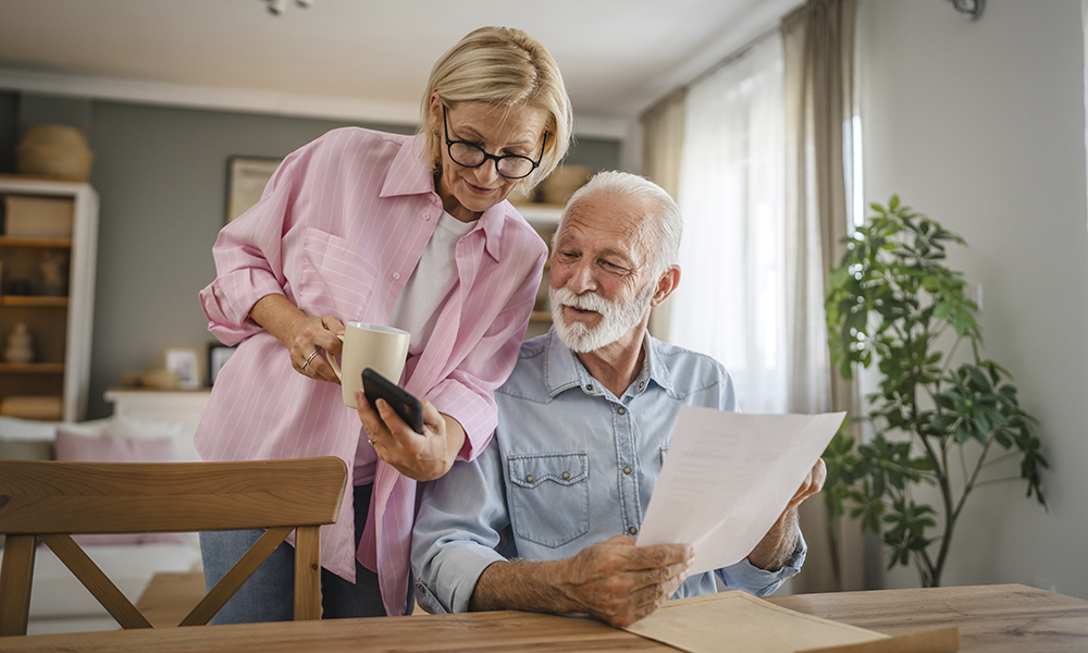 senior,couple,read,a,document,from,envelope,and,use,cellphone