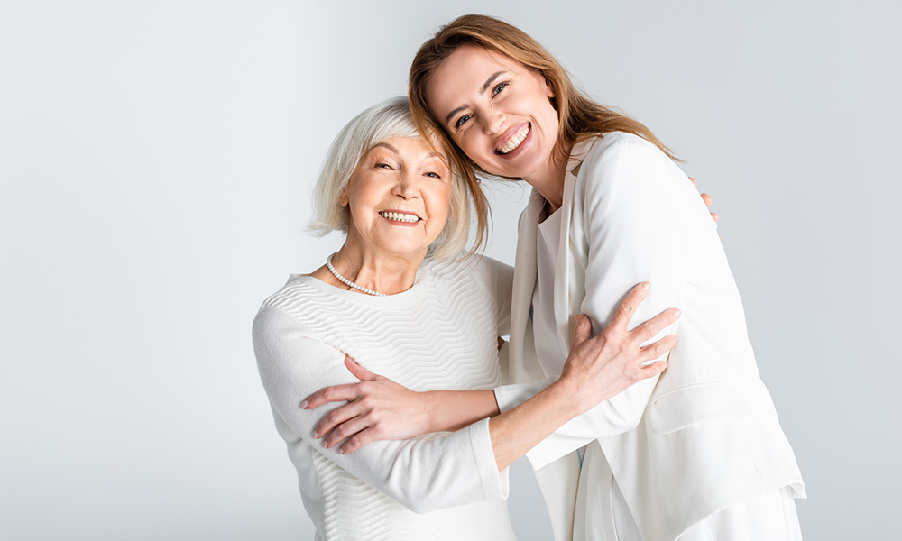 senior,mother,hugging,with,happy,daughter,isolated,on,grey