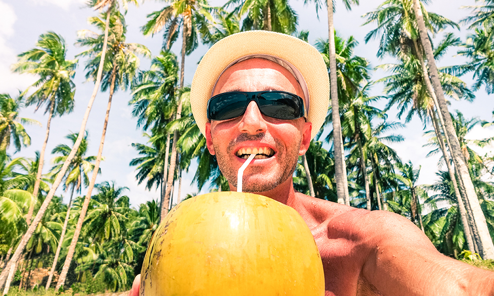 cheerful,man,beach,selfie,drinking,coconut,milk,with,palm,trees