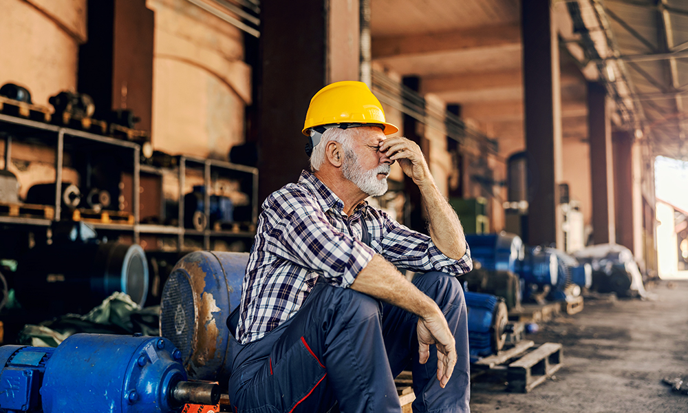 a,worried,senior,factory,worker,is,sitting,next,to,the