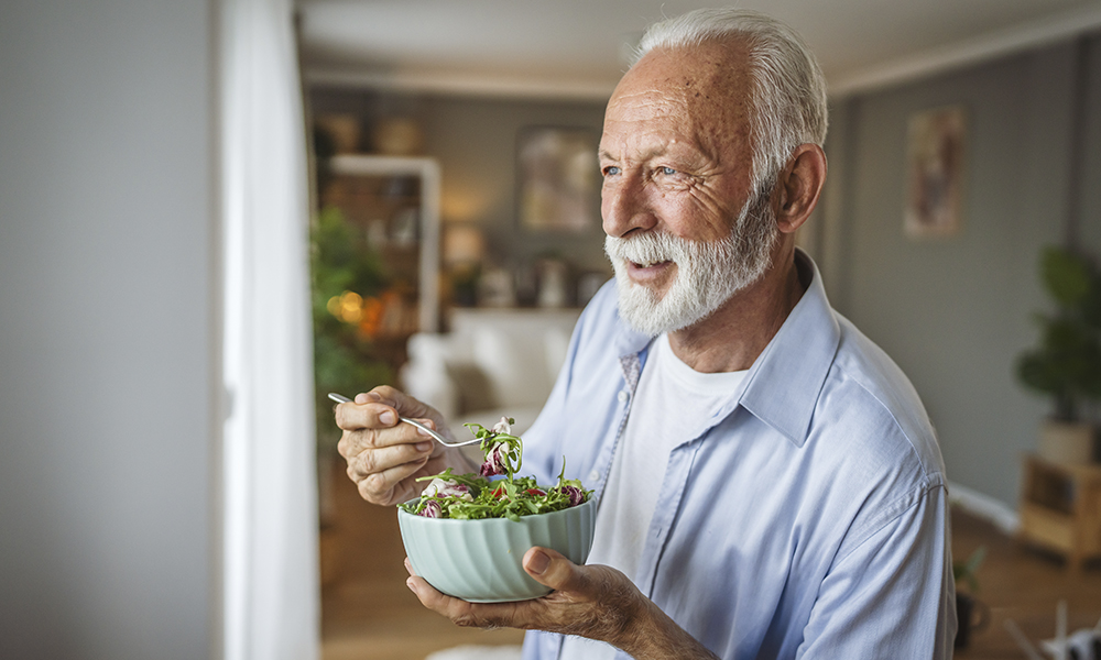 portrait,of,senior,man,stand,at,home,and,eat,salad