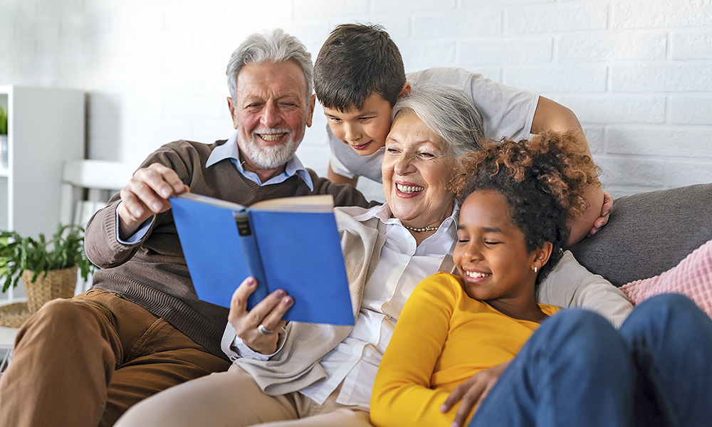 happy,senior,grandparents,having,fun,,reading,book,to,multiethnic,grandchildren.