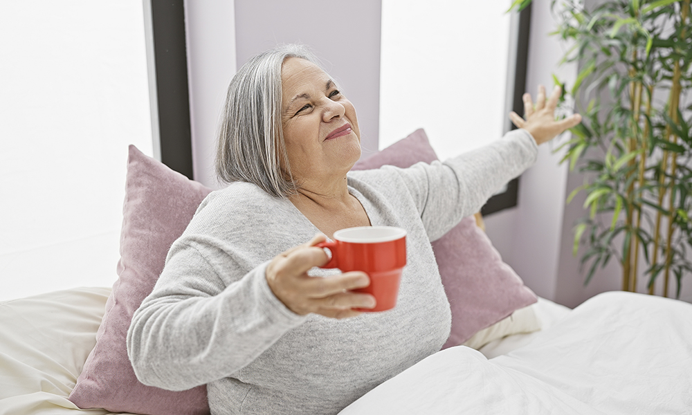 a,smiling,senior,woman,holding,a,red,mug,,stretching,in