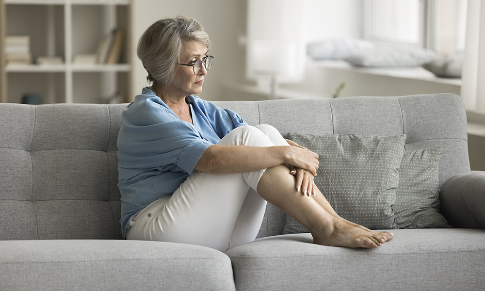 upset,mature,woman,sits,on,sofa,in,living,room,,thinking