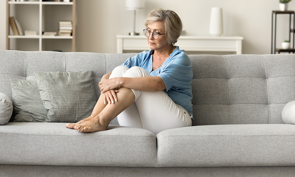 depressed,older,retired,woman,sitting,on,sofa,at,cozy,modern
