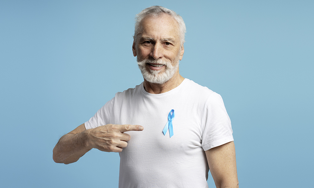 smiling,senior,man,pointing,at,blue,ribbon,pinned,to,his
