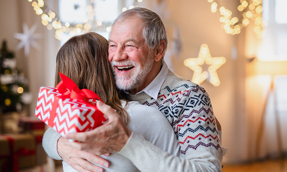 young,woman,giving,present,to,happy,grandfather,indoors,at,home