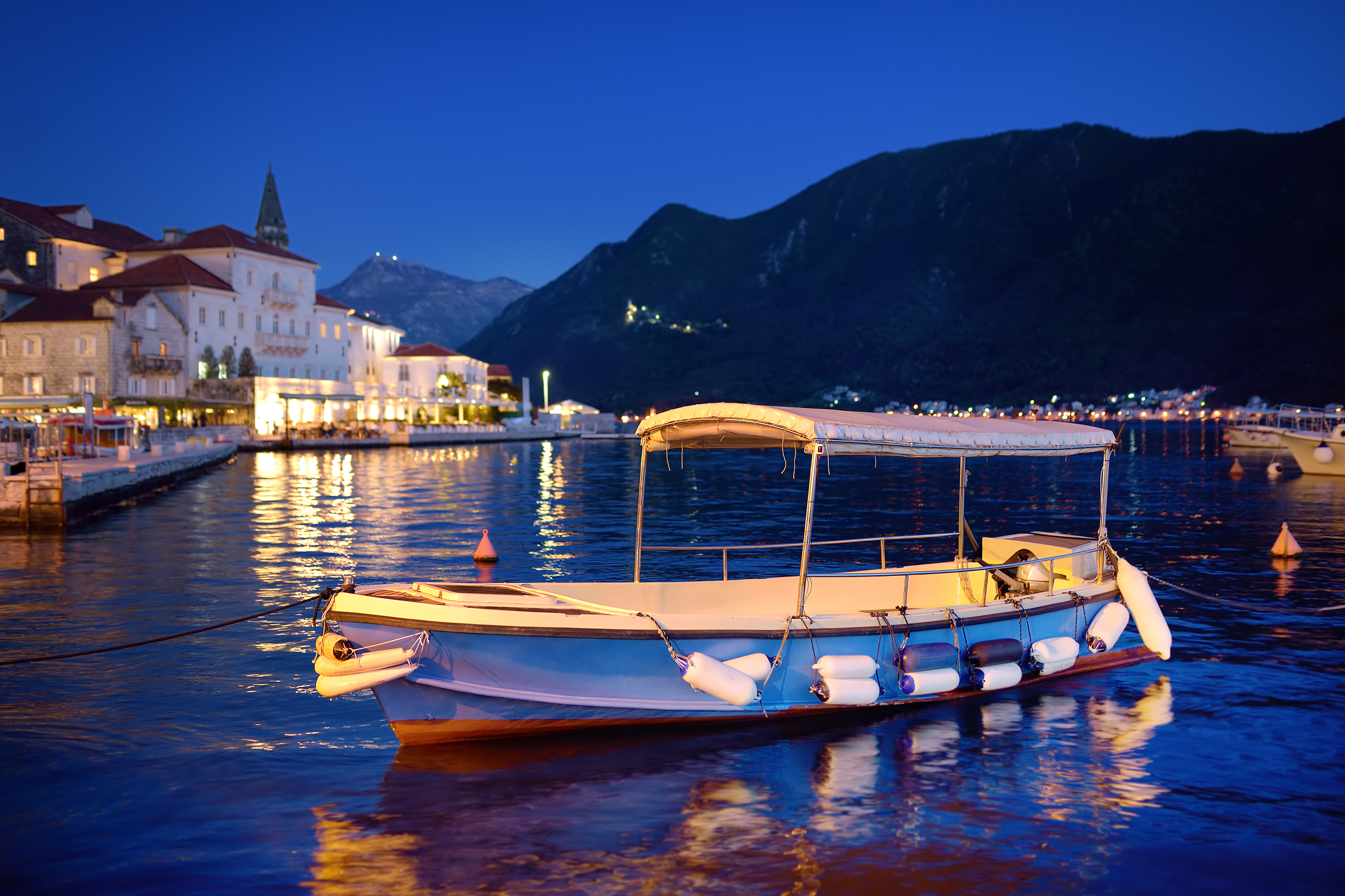 view of ancient picturesque city of perast. old medieval little town with red roofs and mountains on background of famous kotor bay of adriatic sea at blue hour. travel in montenegro.