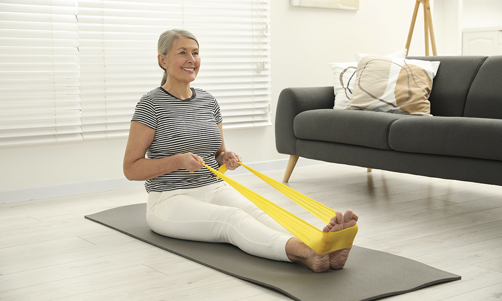 senior,woman,doing,exercise,with,fitness,elastic,band,on,mat