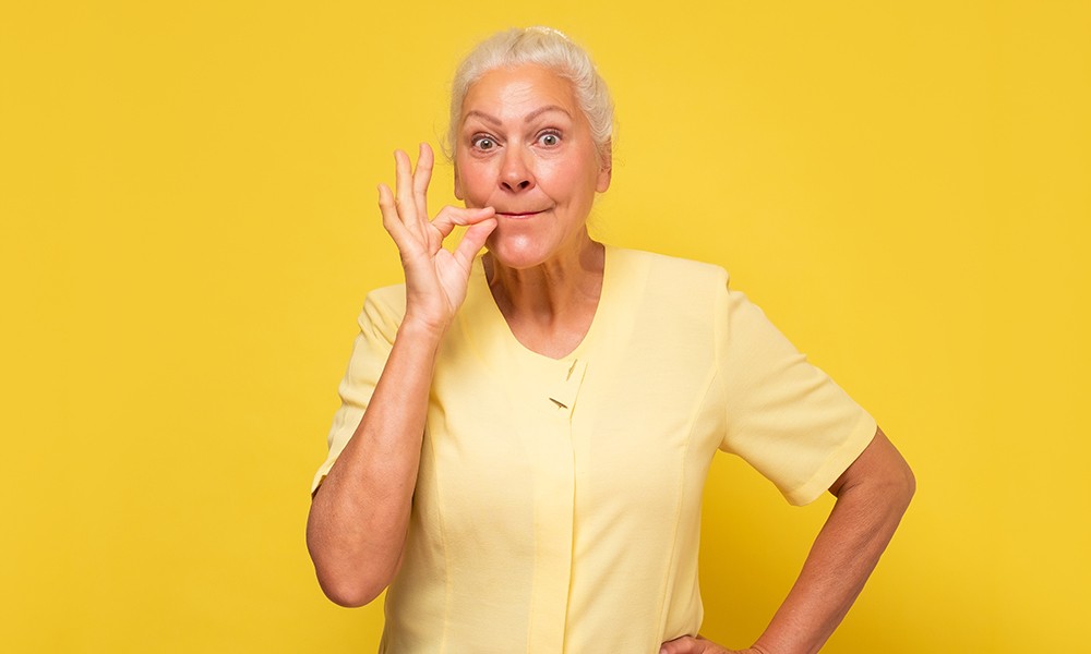 senior,hispanic,woman,showing,silent,gesture,zipping,her,mouth.,studio
