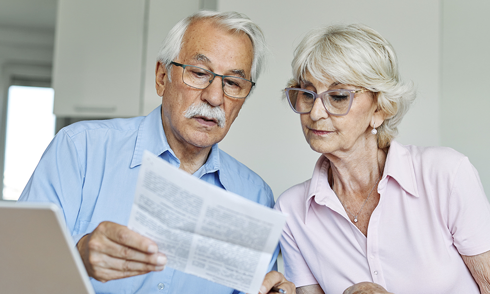 senior,couple,checking,bills,and,calculating,expenses,using,a,laptop