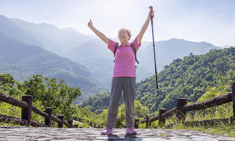 senior,cheerful,woman,on,a,mountain,hike,and,showing,with