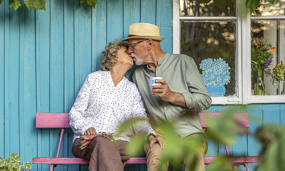 elderly,couple,kissing,in,the,garden,on,a,sunny,day